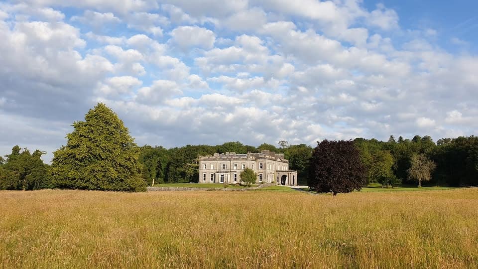 Temple House seen across the lake through long grass in County Sligo