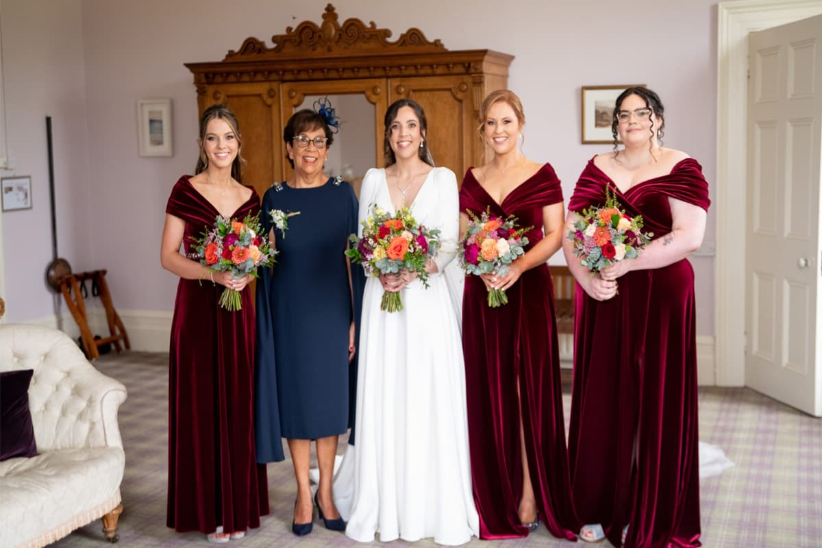 Bride getting dressed in a bedroom at Temple House with the help of others