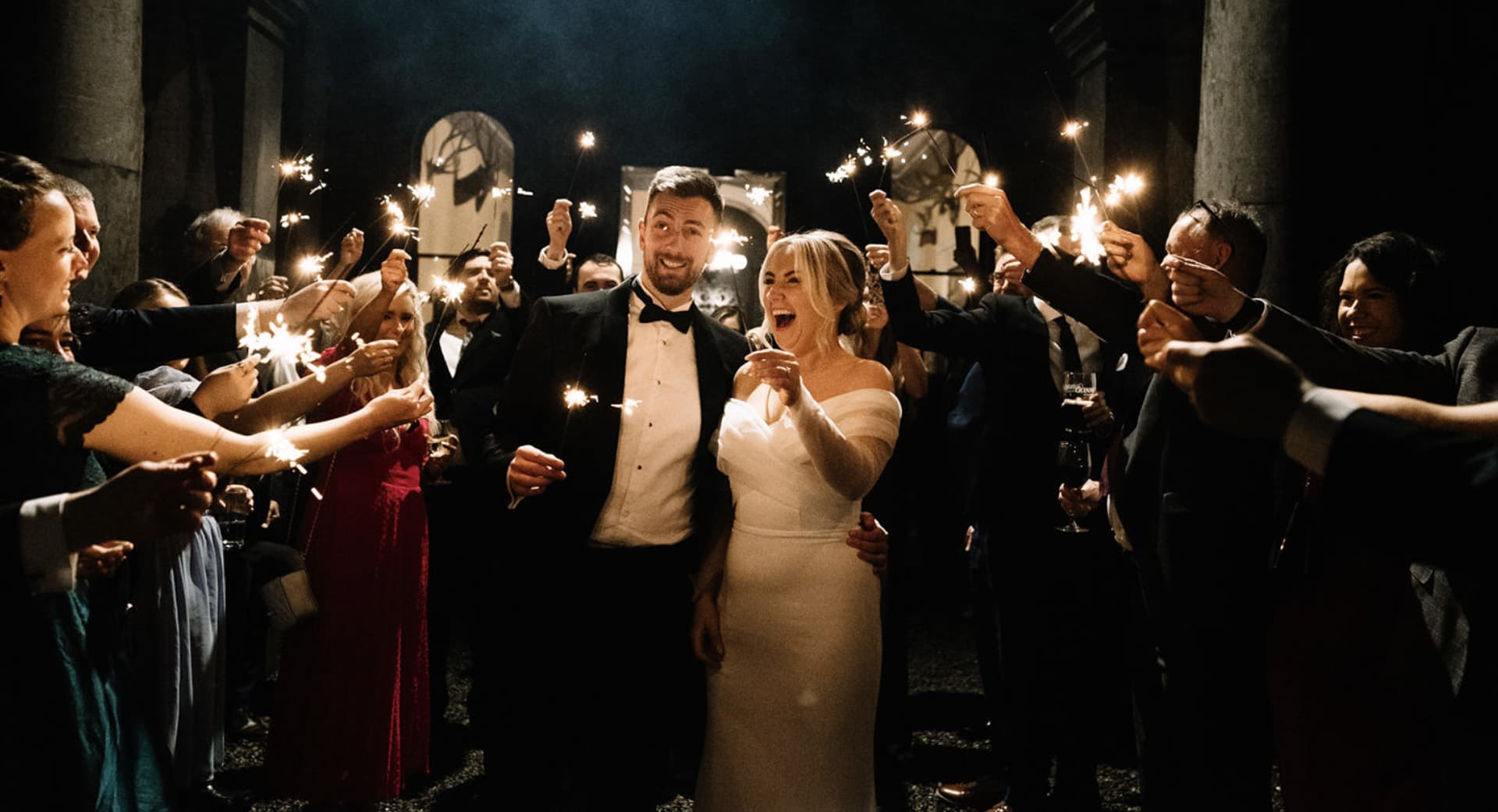 Wedding party holding up sparklers for the couple to walk under at Temple House